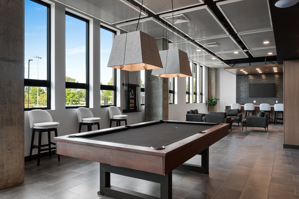 a view of the clubhouse with a pool table in the foreground and tables and chairs in the